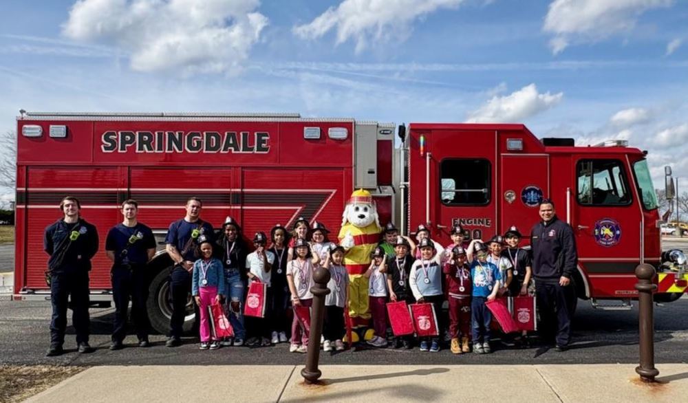 Student winners of the Blazing Vikings for March 2026 standing in front of a Springdale fire truck with four fire fighters and a dog mascot