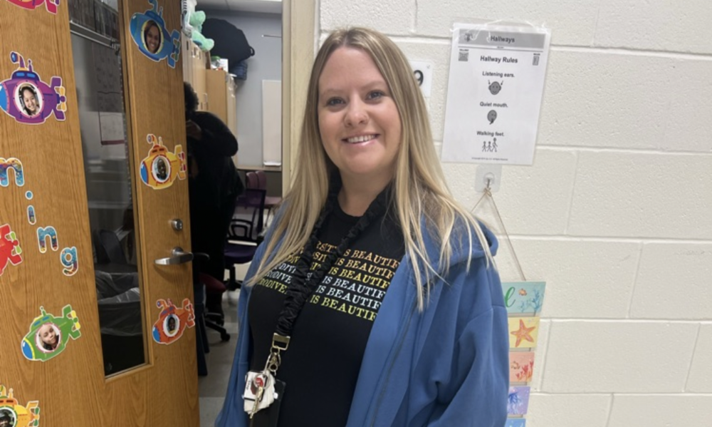 Ms. Ashley Lee in front of her classroom door that is decorated with submarines