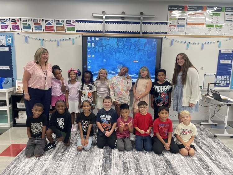 Sharonville Elementary students with two teachers in front of a blue screen and white board in a Sharonville classroom
