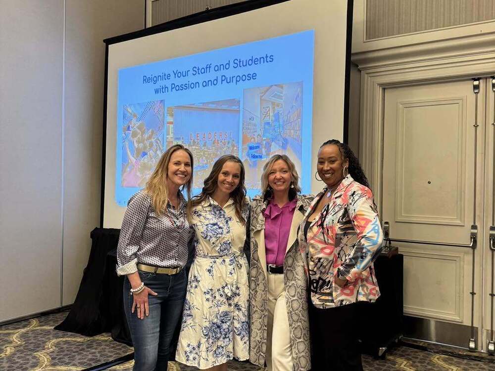 Sharonville Principal Kasi Jordan with three other people in front of a screen that says "Reignite your Staff with Passion and Purpose"