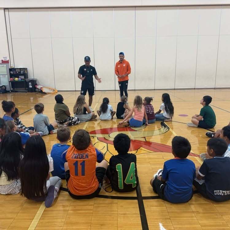 FC Cincinnati players talking to Stewart Elementary students sitting in a circle in the Stewart gym