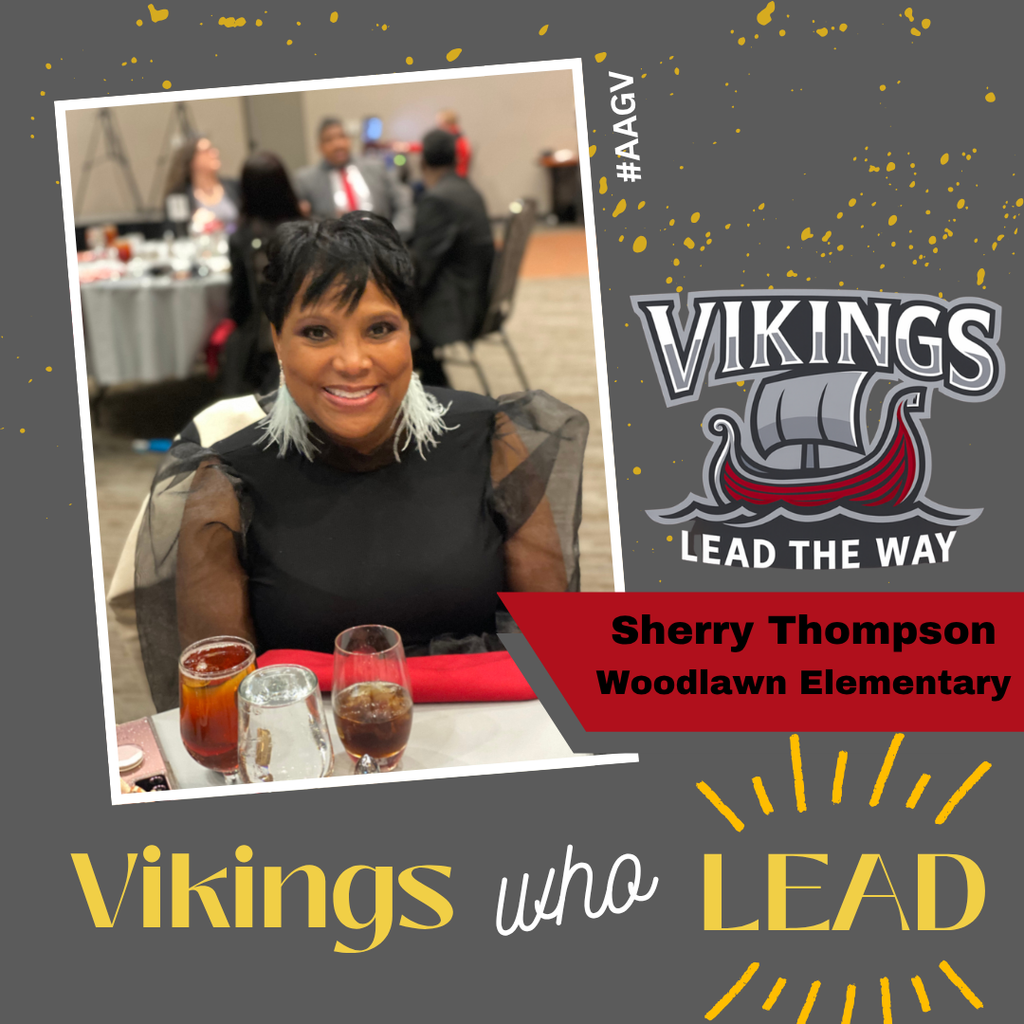 Photograph of Sherry Thompson from Woodlawn Elementary, seated at an event table wearing an elegant black dress with sheer sleeves and a short black and white hairstyle, smiling at the camera. Three beverages in glasses sit on the red-clothed table in front of her. Other attendees are visible in the blurred background of what appears to be a banquet or conference setting. The image is displayed in a tilted white frame against a gray background decorated with gold confetti. The Vikings logo, featuring a Viking ship with 'Lead The Way' motto, appears in the top right. Text at bottom reads 'Vikings who LEAD' with 'Vikings' and 'LEAD' in gold and 'who' in white script. A red banner identifies 'Sherry Thompson, Woodlawn Elementary.' Hashtag #AAGY appears vertically along the right edge.