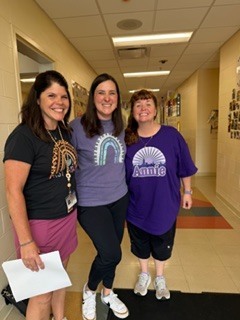 three people wearing purple clothing standing in a hallway
