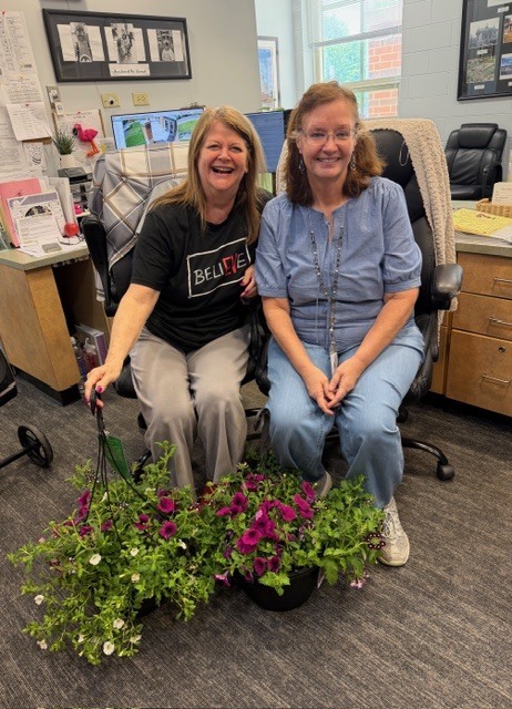 two people sitting in chairs with flowers in front of them.