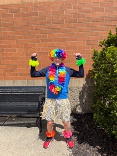 student wearing flowers and standing in front of a bench 