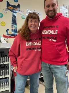 two people wearing sweatshirt with red and letters 