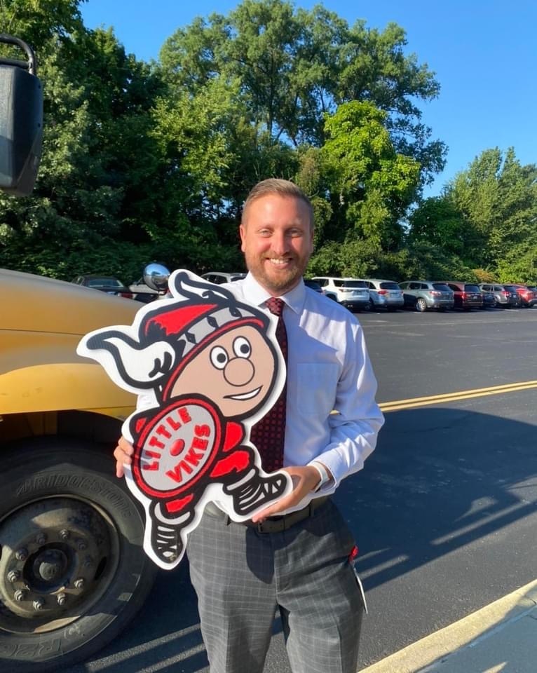 person holding a little cut out near a bus
