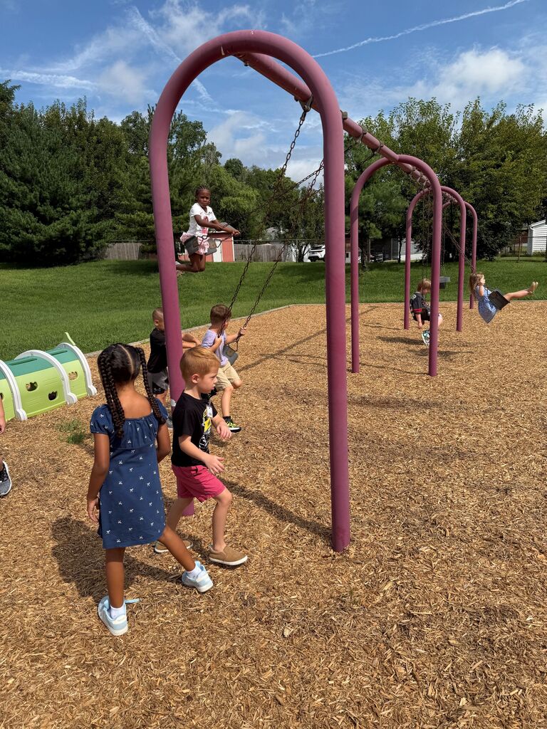 Six children at Evendale Elementary playing on the playground and swing set.