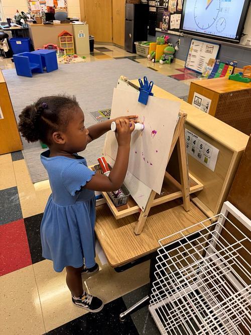 student standing at an easel with dot markers