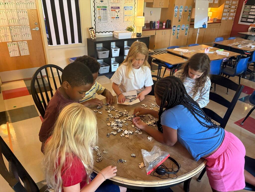 students at a table with puzzle pieces