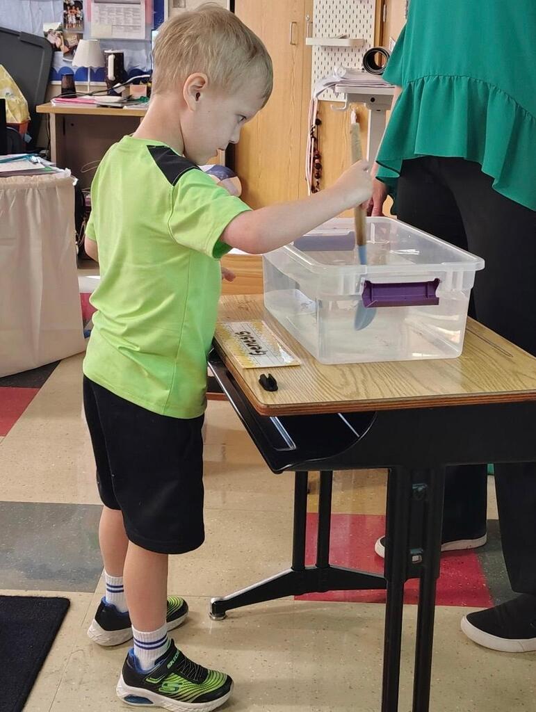 student holding a spoon in water with apples