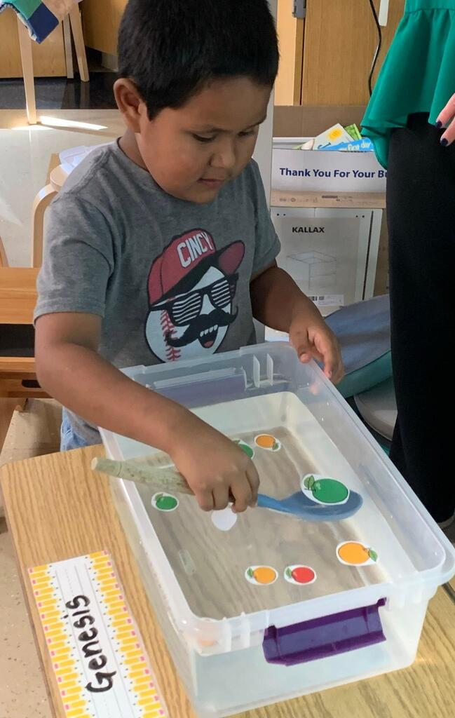 student holding a spoon in water with apples
