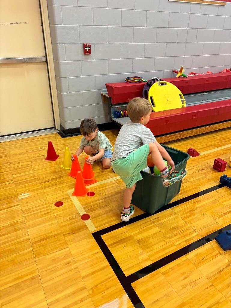 students in the gym with tubs and balls 
