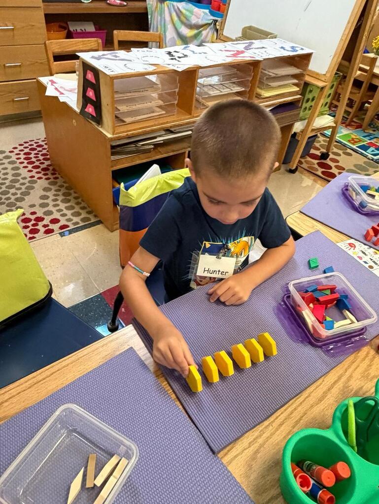 student at a table with math blocks