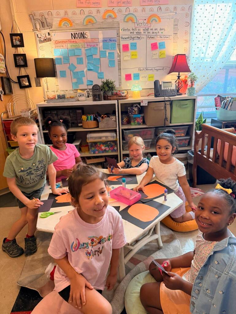 people in a classroom around a table making crafts