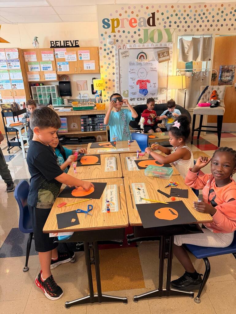 people around a table in a classroom making crafts