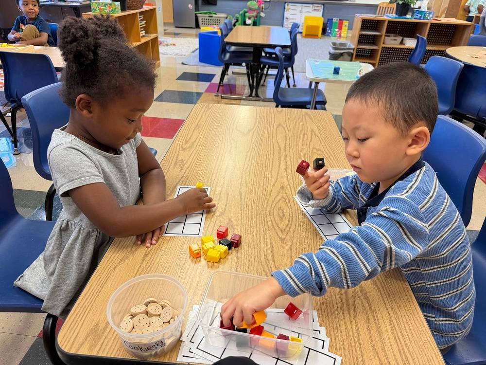 students at a table with math blocks 