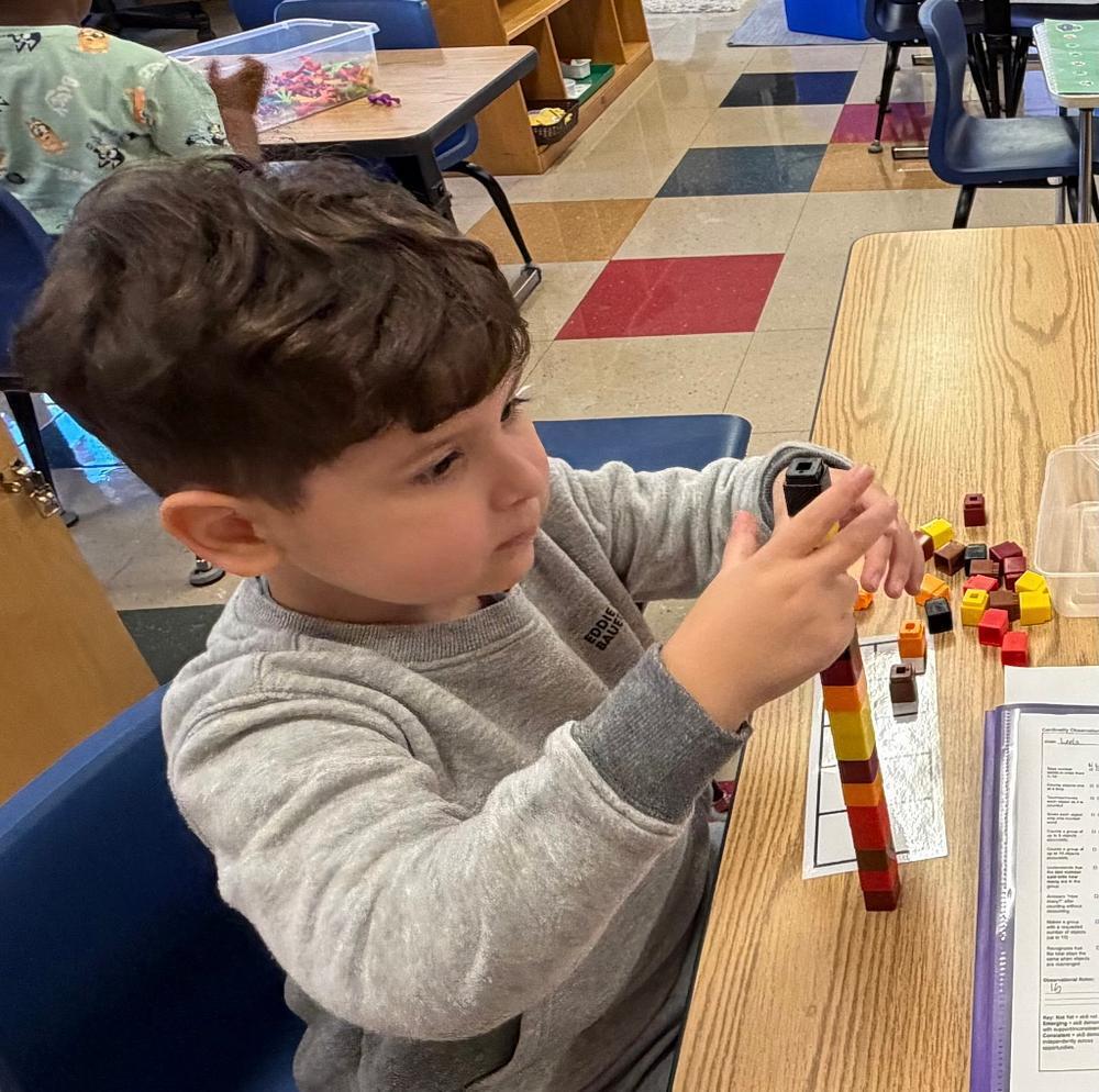 student at a table with math blocks