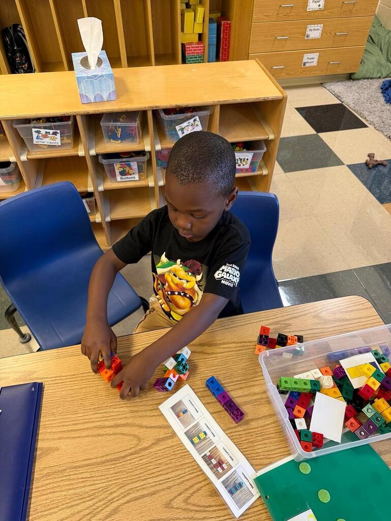 student at a table with math blocks