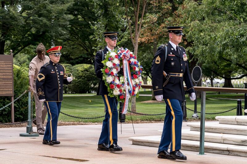 Three officers march towards the Tomb of the Unknown Solider. The middle one is holding the wreath.