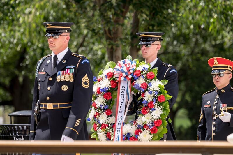 standing among the marble colonnades of the Memorial Amphitheater as the wreath — bearing the department's name in red, white, and blue — was carried forward and placed at the Tomb by the U.S. Army's elite Tomb Guard sentinels.