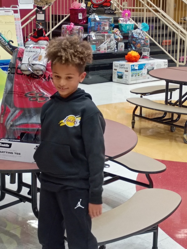 Student next to a prize basket with lots more fun prizes behind him on the staircase.