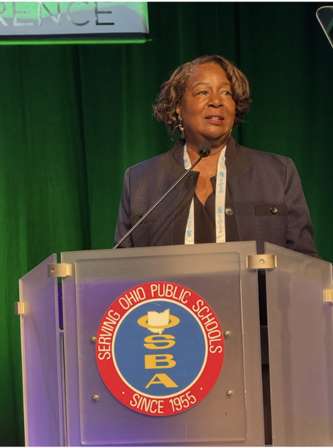 Mary Cleveland giving acceptance speech at podium with OSBA logo on the front of the podium