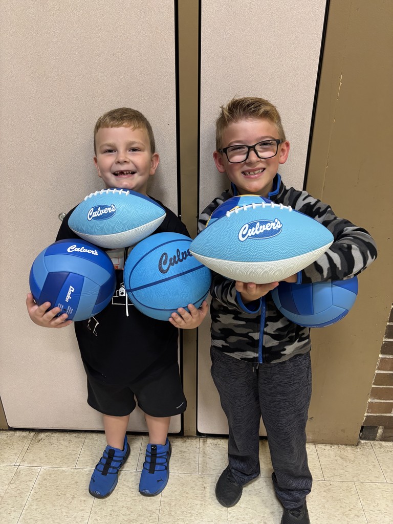 Two Jefferson students holding footballs, basketballs, and volleyballs from Culvers to be used on the playground