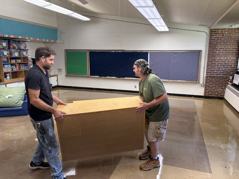 Custodians moving furniture into classroom