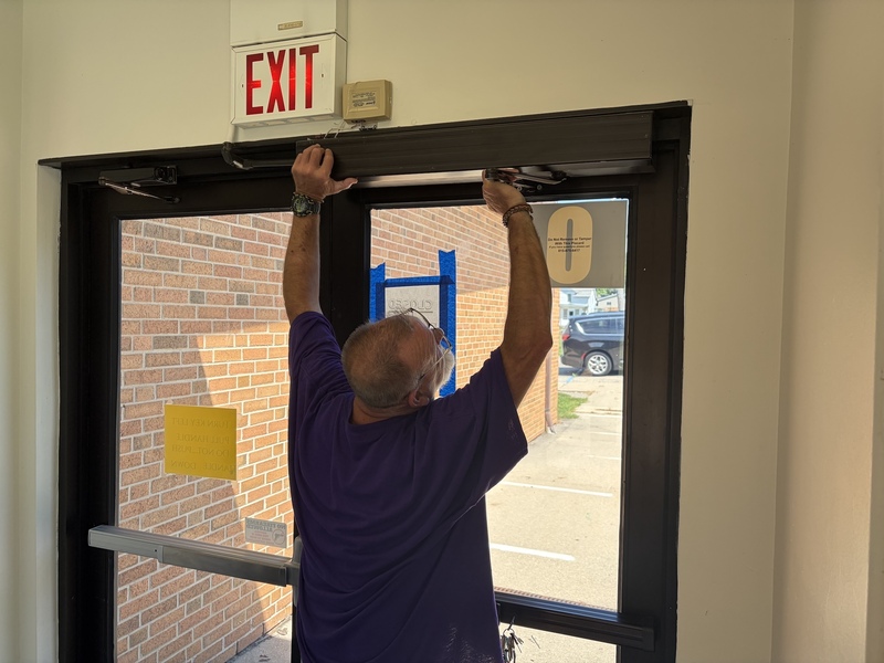 Custodian repairing a door closer