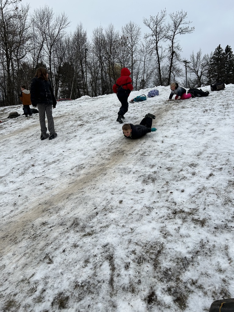 Boy sliding down a snowy hill on his stomach