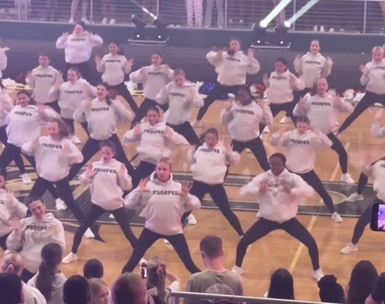 Dance members pose with their hands up by their shoulders on the gym floor