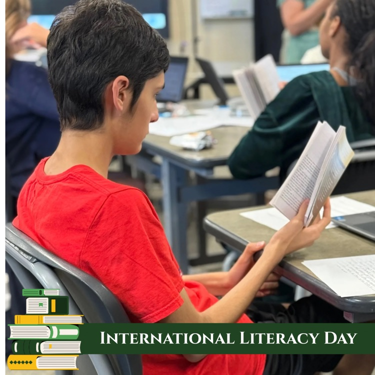 Junior Daniel Campos reads Of Mice and Men during class. Graphic banner says International Literacy Day with a stack of books in the bottom left corner.