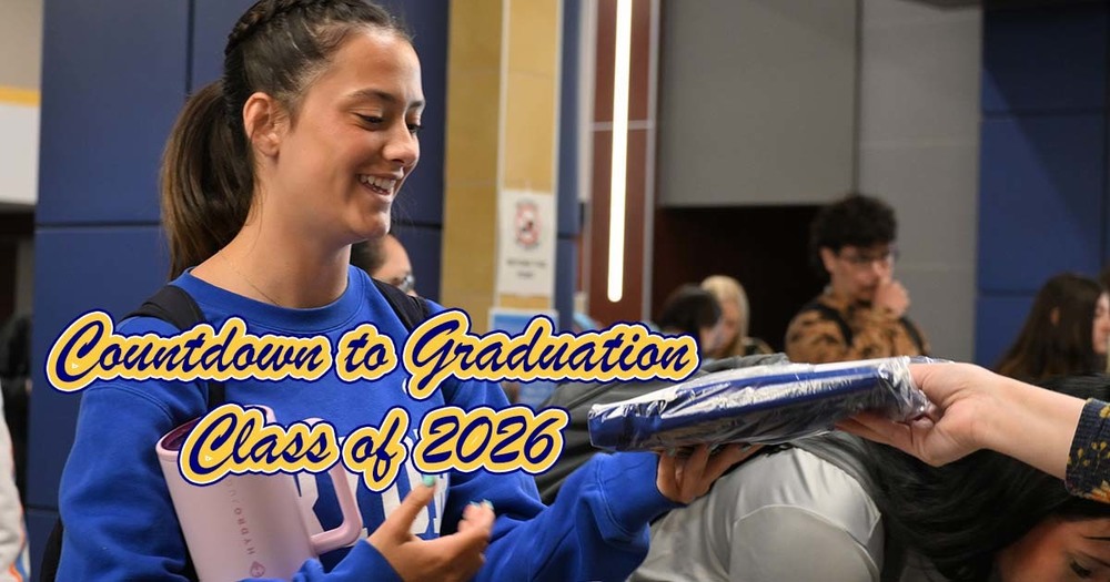 girl picks up graduation cap and gown