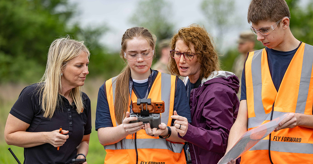 students and adults check drone controls
