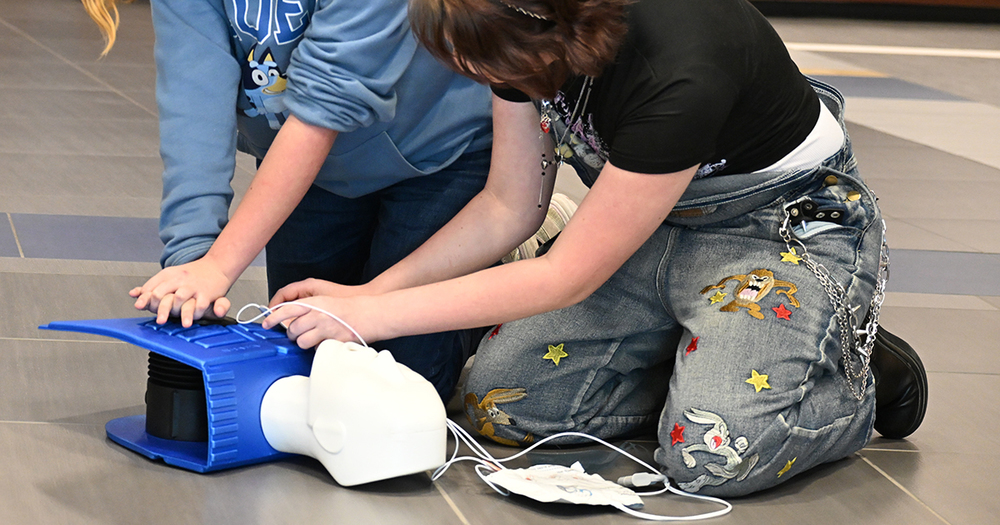 students performing cpr on manikin