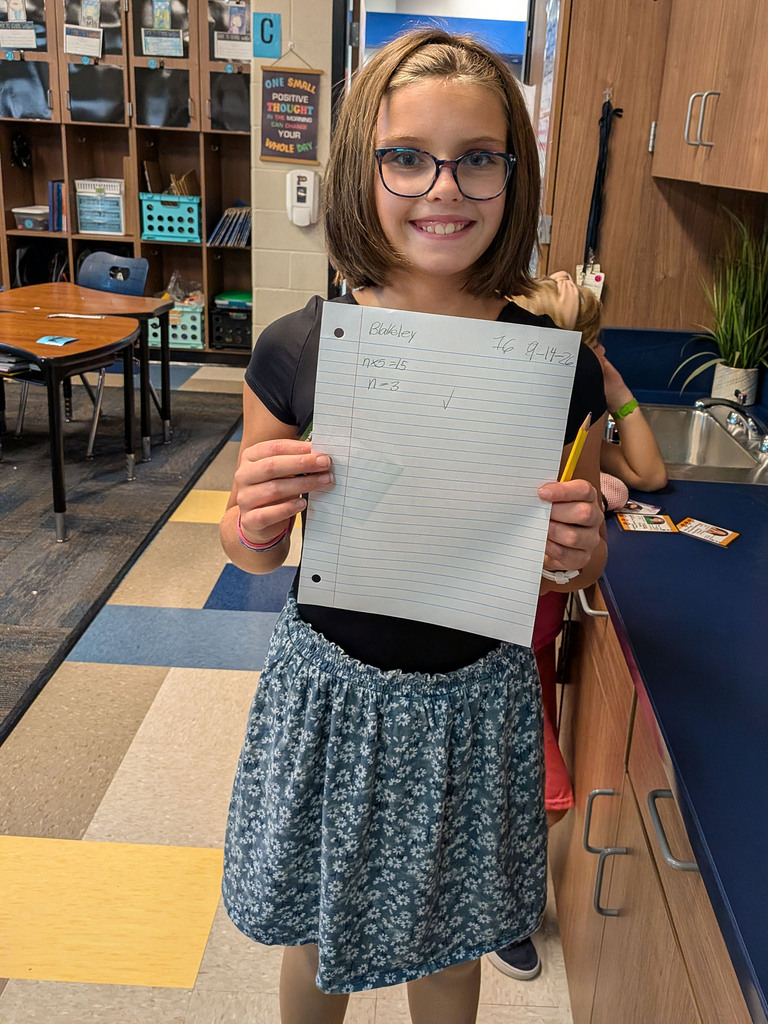 girl holding up algebra paper