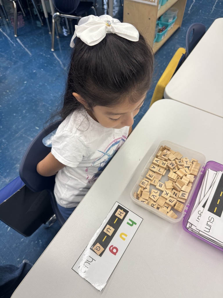 Child using Scrabble tiles to spell a word