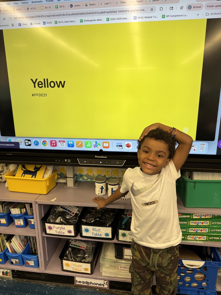 One student posing in front of a big yellow screen showing the word "yellow"