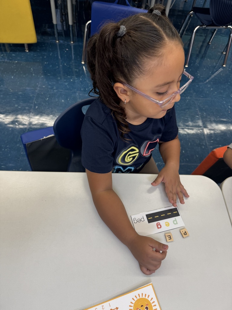 Child using Scrabble tiles to spell a word