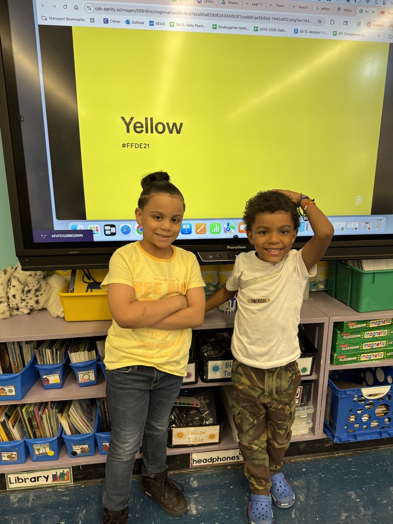 Two students posing in front of a big yellow screen showing the word "yellow"