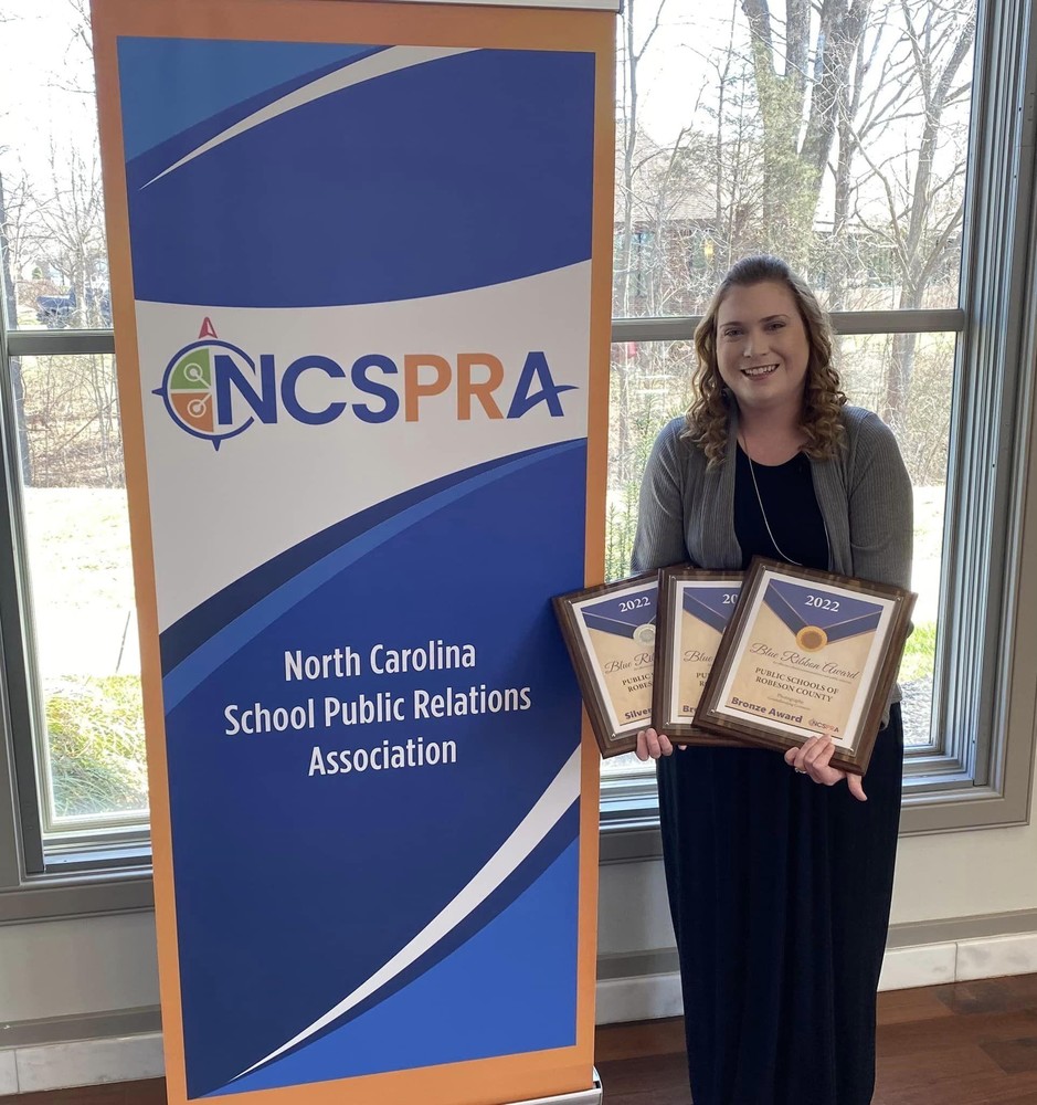 PSRC Chief Communications Officer Jessica Horne stands recently with North Carolina School Public Relations Association Blue Ribbon Awards for the district's communication excellence