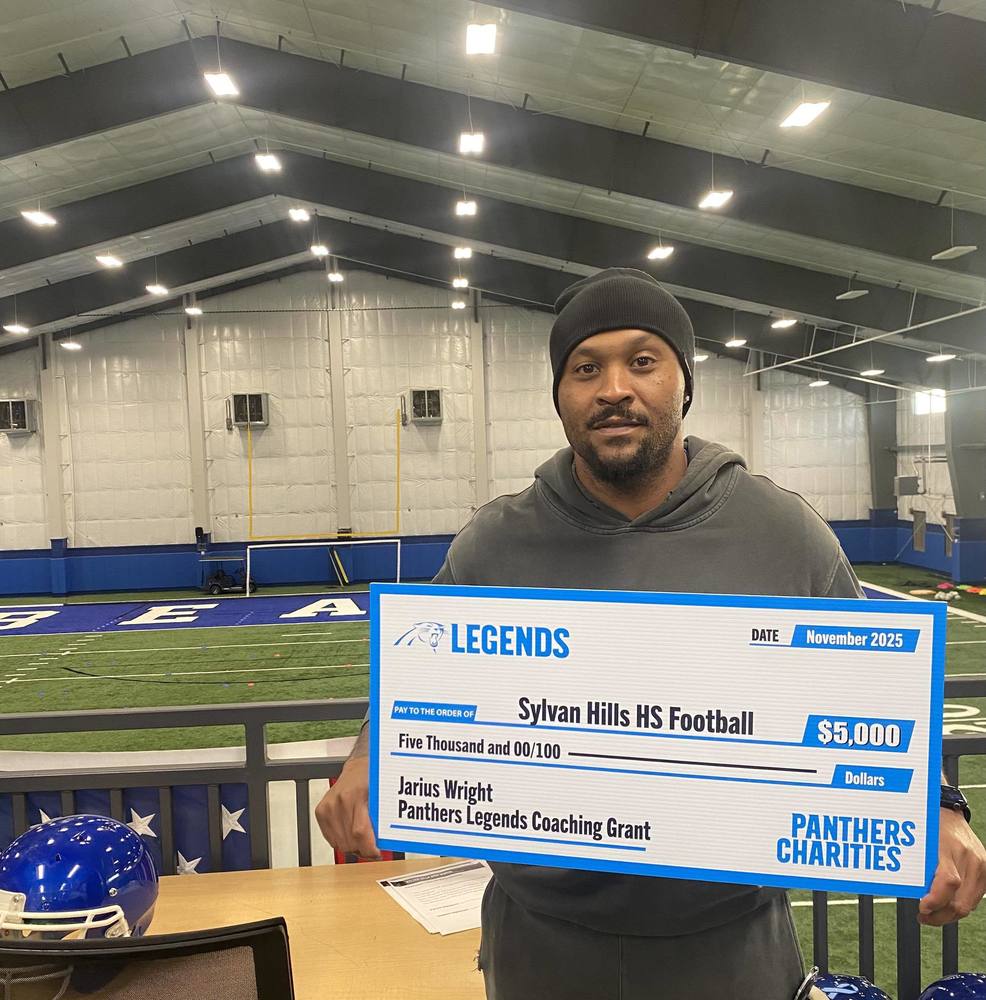 Assistant Coach and former NFL wide receiver Jarius Wright holing a check from Panthers Legends Foundation for $5,000 inside the Sylvan Hills Bears indoor practice facility.
