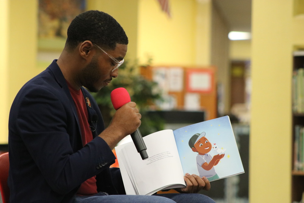 Kyzyl Tenpenny reading his book "Daddy Daddy, Son Son" to students inside Landmark Elementary