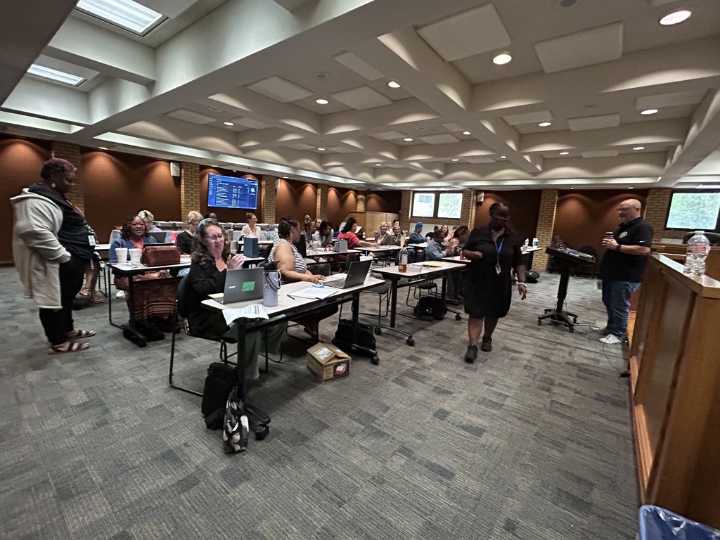 Central Office staff present a training and professional development to a group of PCSSD registrars  while seated at tables in the boardroom.