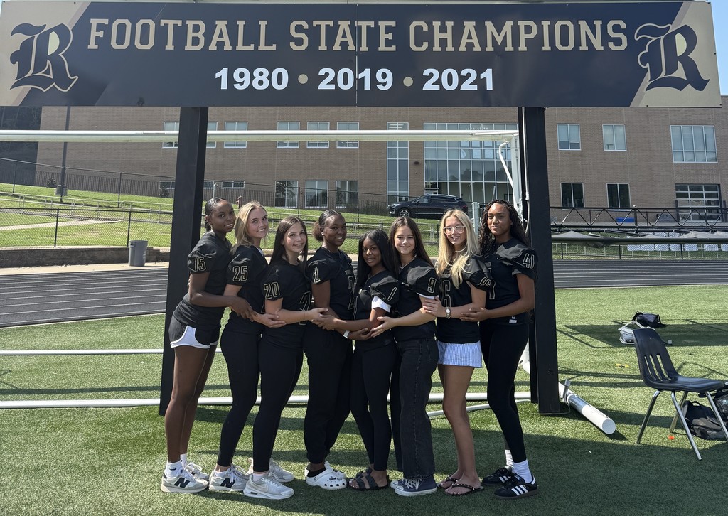 Joe T. Robinson High School's 2025 Homecoming Court in football jerseys standing on a sports field in front of the scoreboard reading "Football State Champions 1980 • 2019 • 2021".