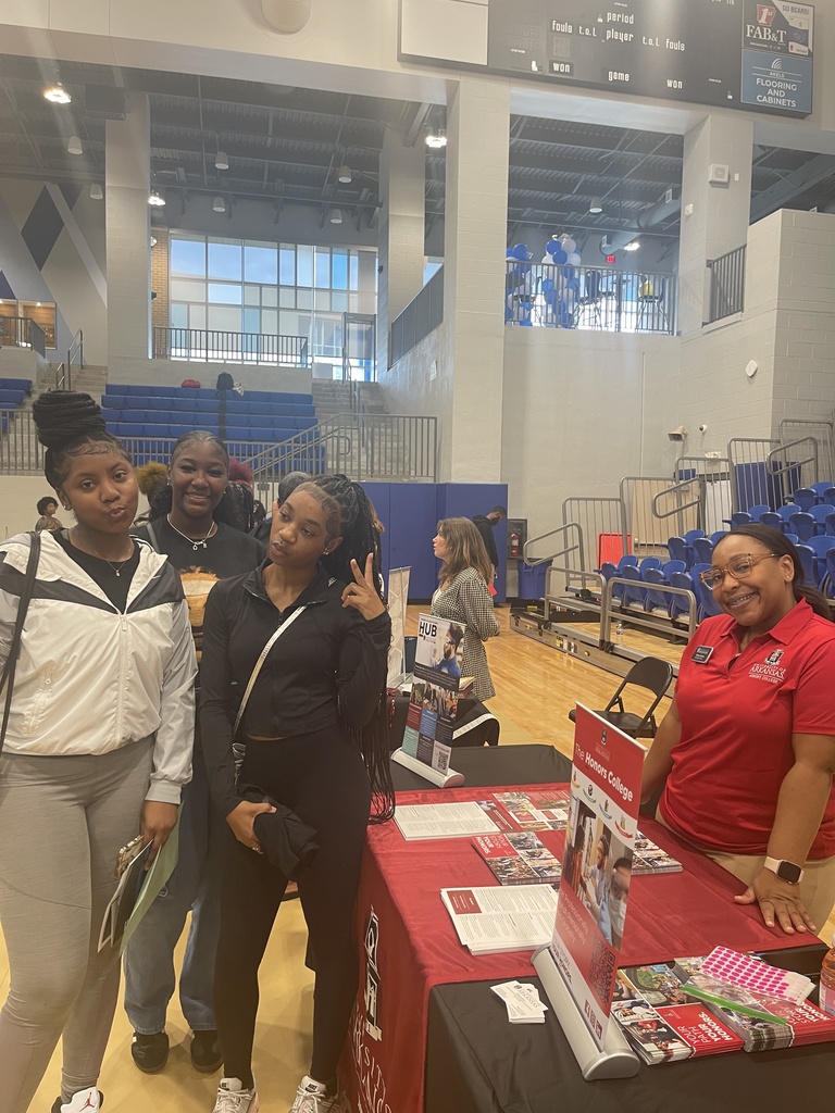 Students posing with college fair table and recruiter