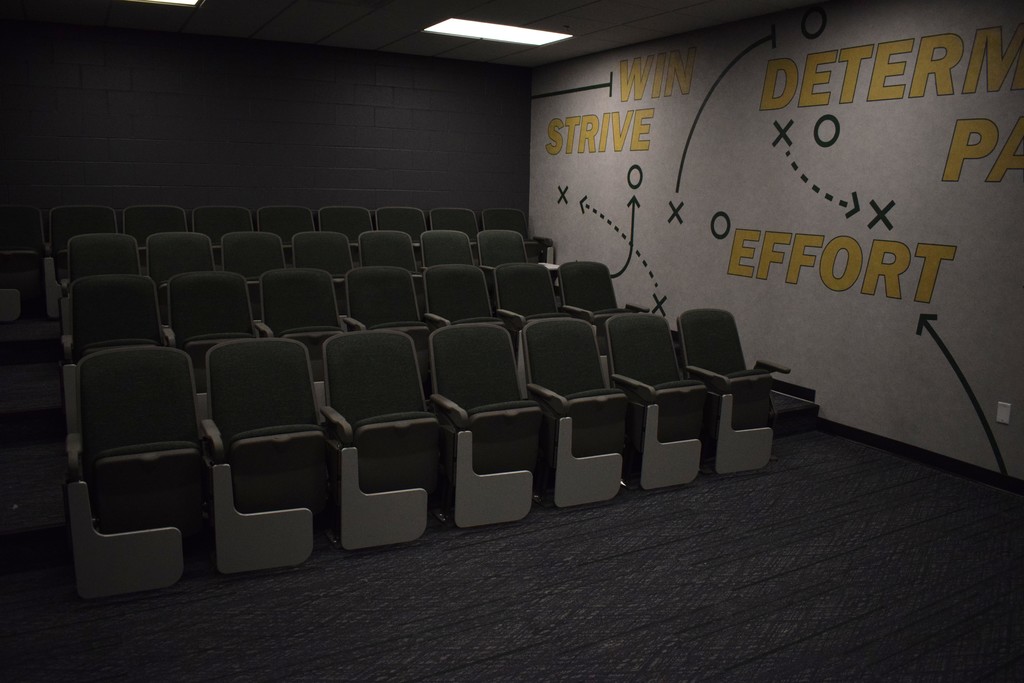 Four rows of chairs in a film study room with the words win, strive, effort, determination, and passion on the wall.