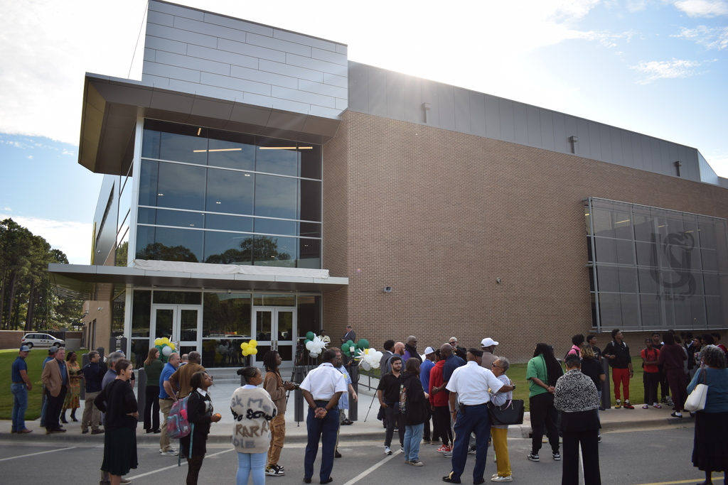 Exterior of the Raymond A. Cooper Arena without its name revealed. A crowd is gathering for the unveiling.