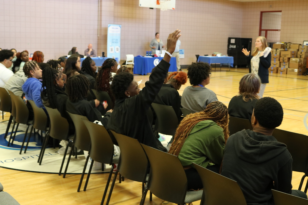 A group of people sitting and listening attentively in what appears to be a classroom or community center setting.